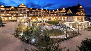 A large, multi-story hotel with a courtyard featuring a pond and stone structures. - Hotel Bania Thermal & Ski (Bukowina Tatrzanska)