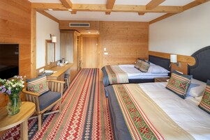 A wooden room with two beds, a desk, and a TV.