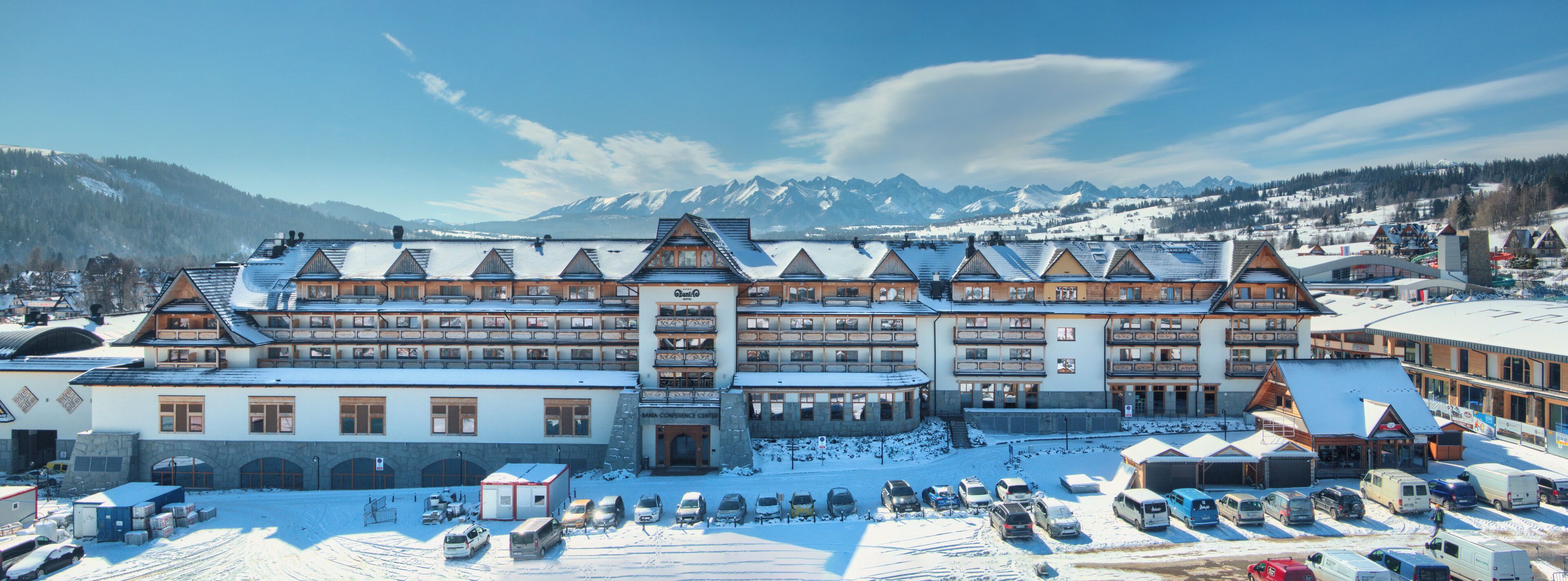 A large hotel with multiple floors and a ski resort in the background.