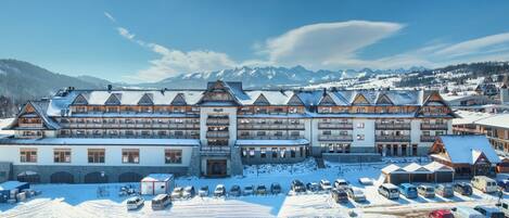 A large hotel with multiple floors and a ski resort in the background.