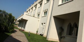 A modern hotel with a clean, white facade, a paved walkway, and neatly trimmed greenery. - Palazzo Giordano Bruno (Nola)