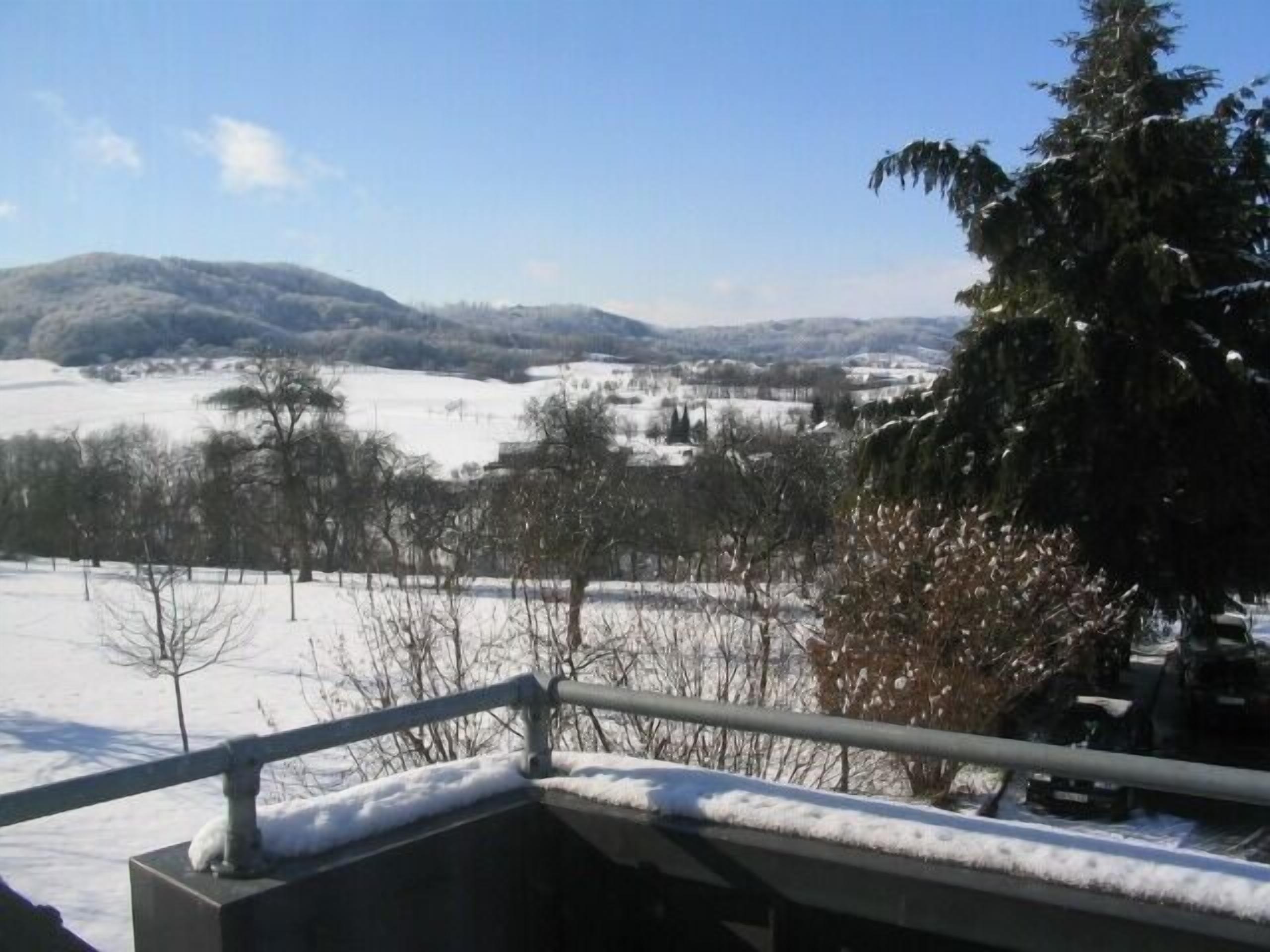 A snowy landscape with a view of distant hills and trees.