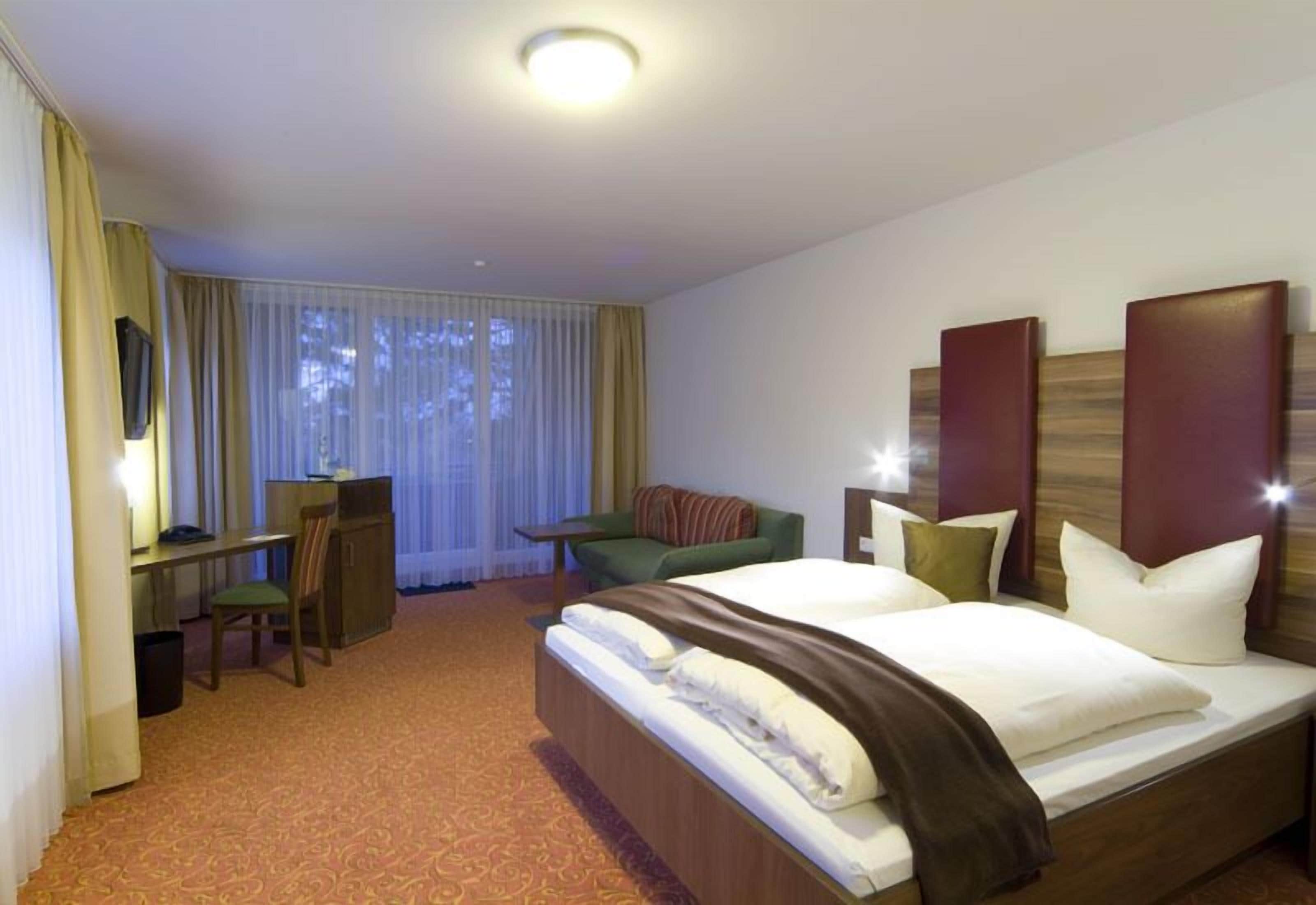 Ein Hotelzimmer mit einem großen Bett, einem Schreibtisch, einem Sessel und einer Couch.