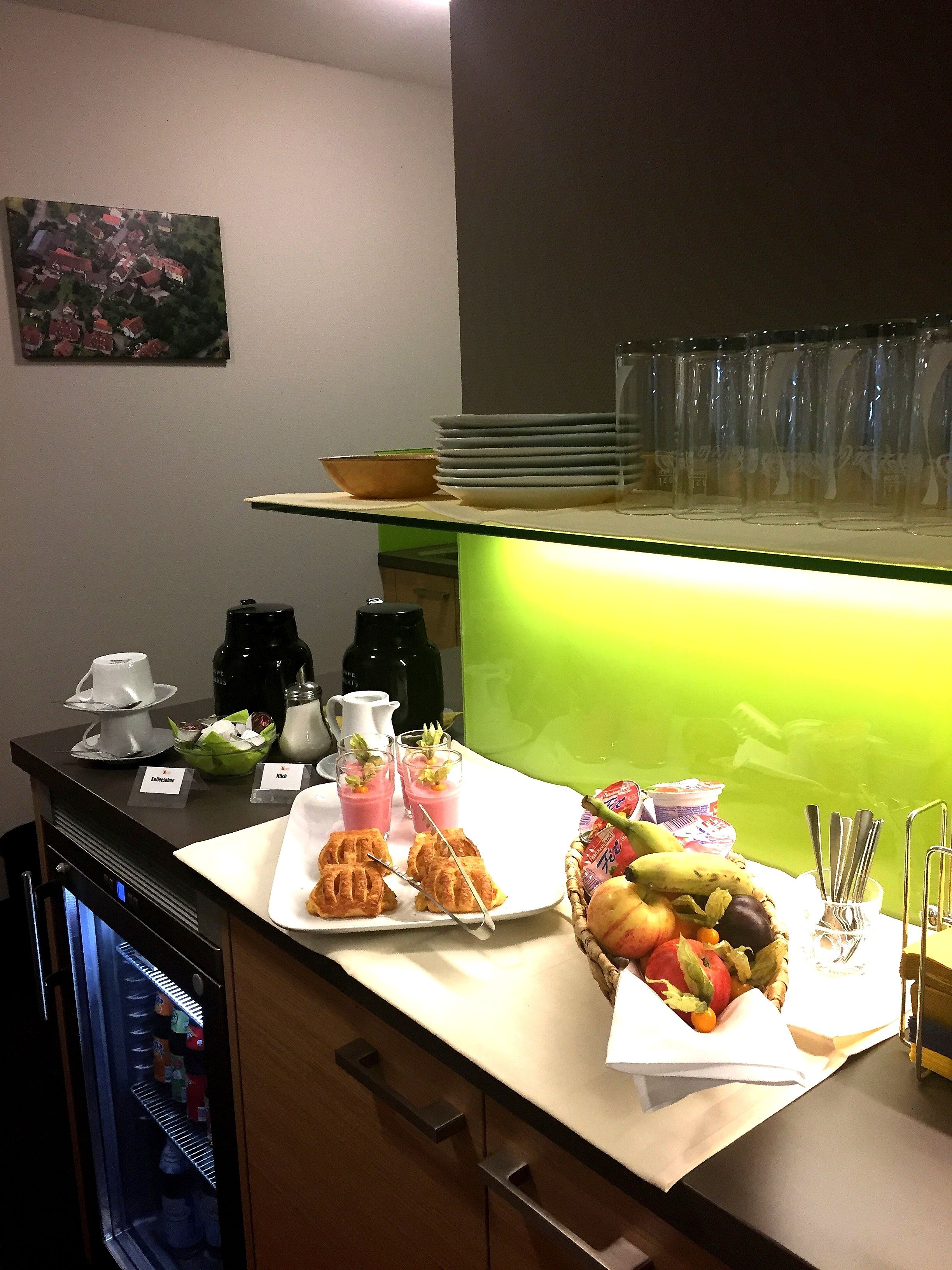 Montaje de bufé con platos de comida, una cesta de frutas y una estación de café.