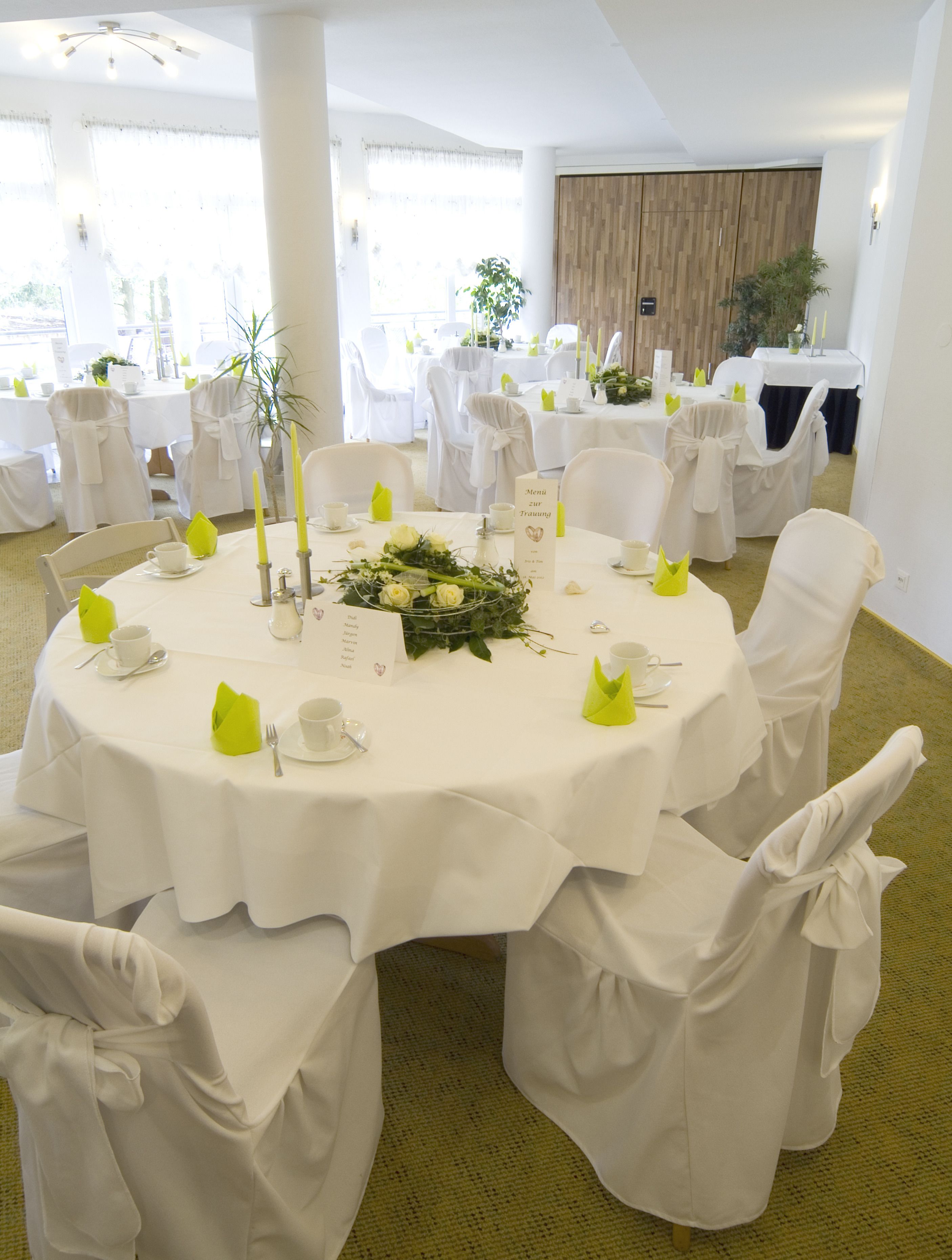 A round table with white tablecloths, yellow napkins, and a floral centerpiece.