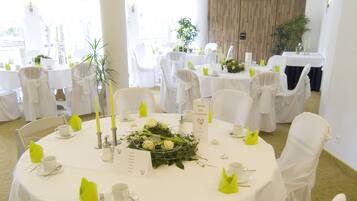 A round table with white tablecloths, yellow napkins, and a floral centerpiece.