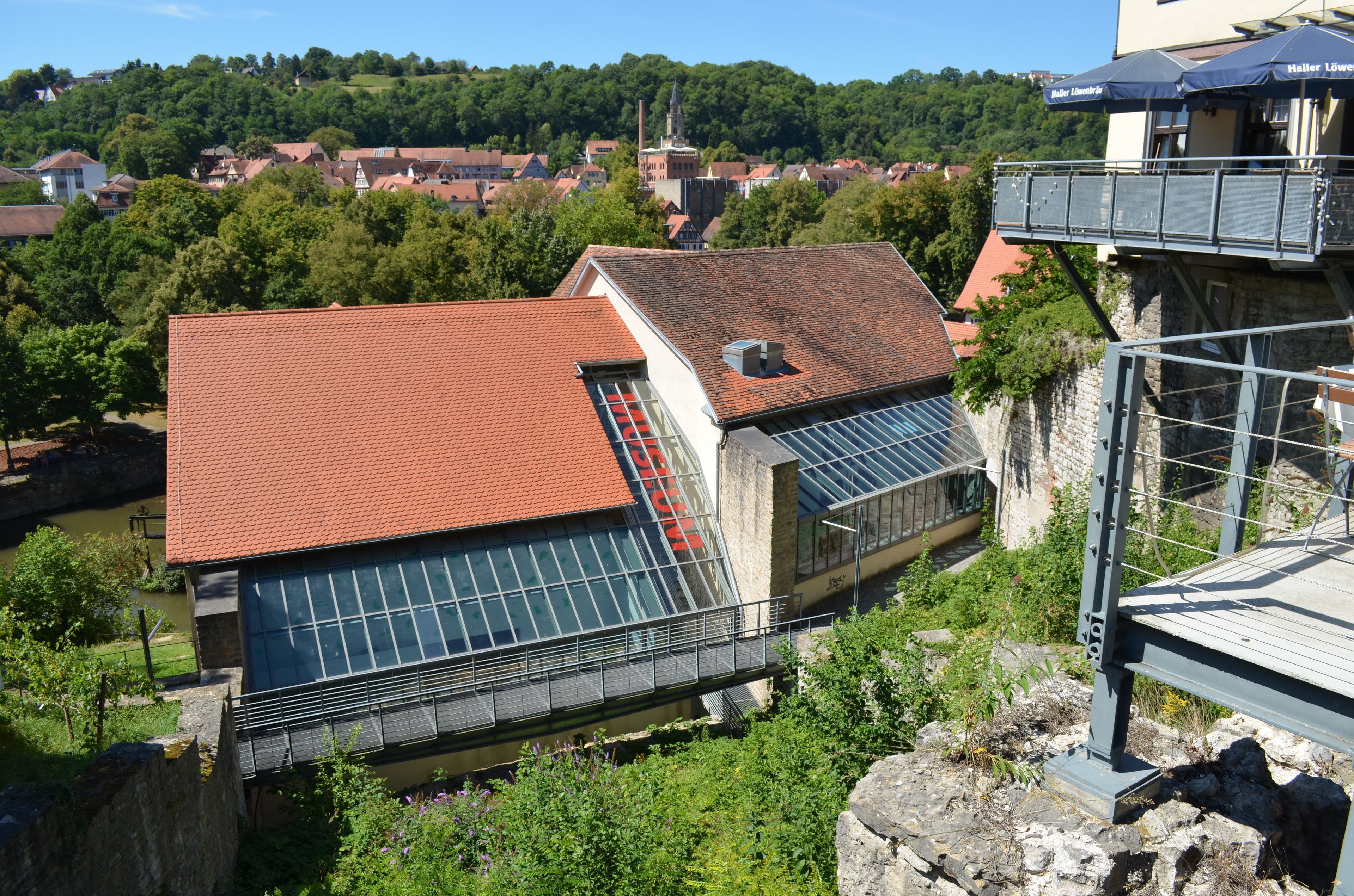 A building with a red-tiled roof, large windows, and a stone base.