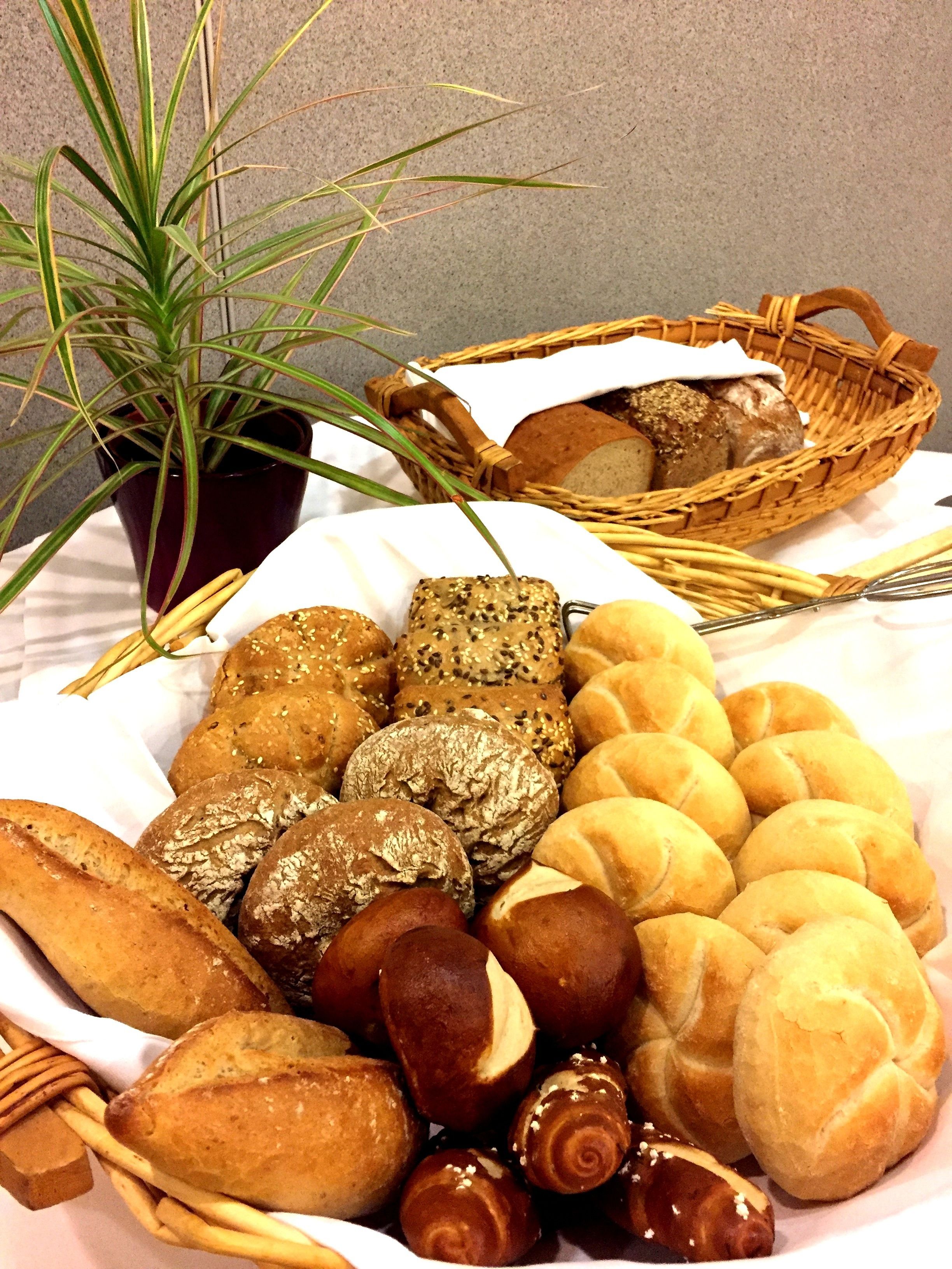 Variedad de panes y pasteles en cestas, una planta en maceta y una cesta de mimbre con pan.
