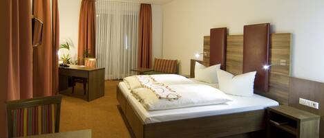 A hotel room with a bed, bedside tables, a desk, and a chair.