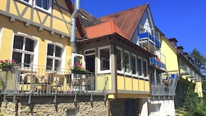 Ein traditionelles europäisches Gebäude mit einer Steinfassade, zahlreichen Fenstern und einem Balkon mit Außenmöbeln.