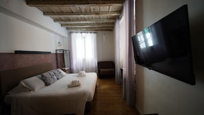 Habitación de hotel con dos camas, televisión, techo de madera y vistas al exterior.