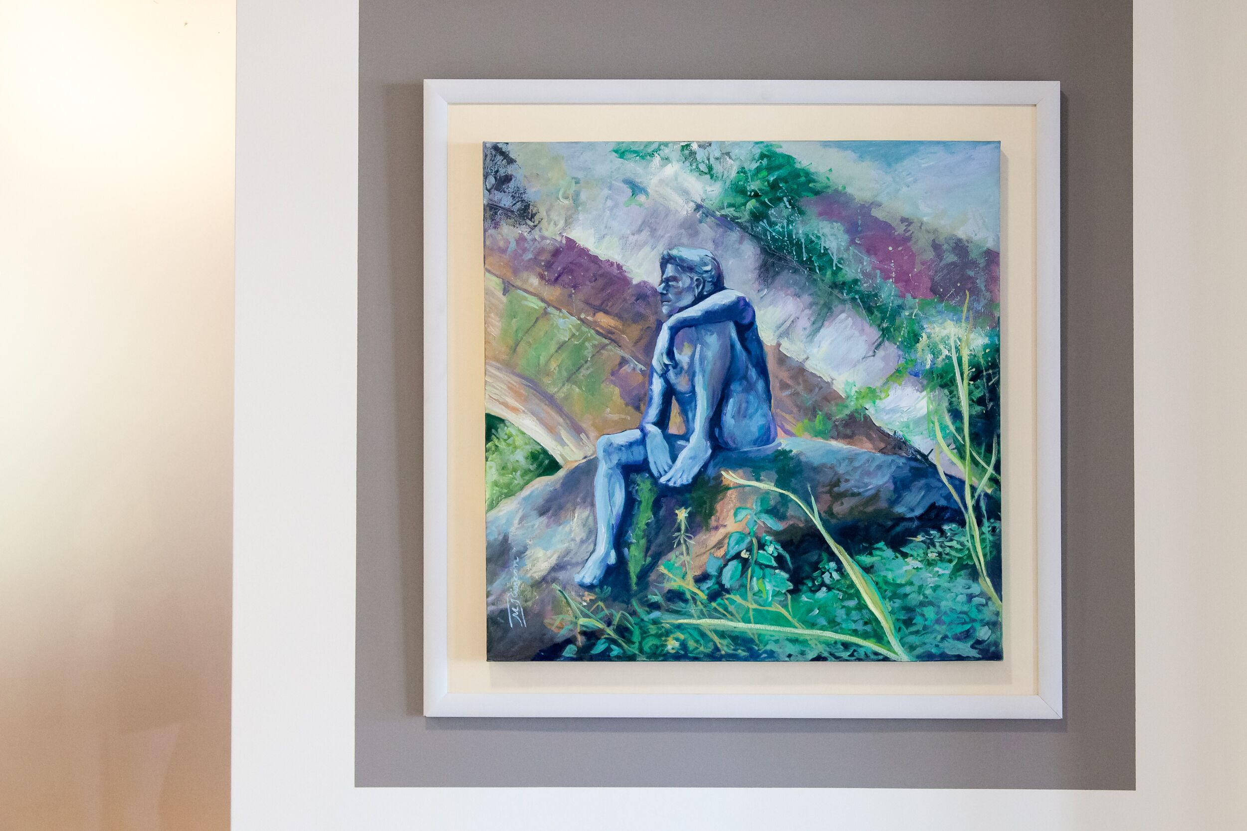 A framed painting of a seated figure on a rock with abstract background.