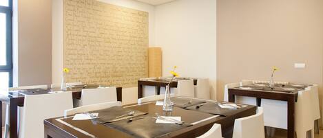 A dining area with tables set for four, white chairs, and a large wall with handwritten notes.