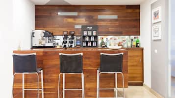A bar area with a coffee machine, espresso machines, a coffee station, and bar stools.
