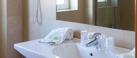 A bathroom with a white sink, a mirror, a hairdryer, and a towel rack.