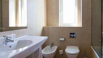 A modern bathroom with a large sink, bidet, toilet, and a glass shower enclosure.