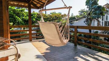 A wooden deck with a hanging hammock chair and a wicker table.