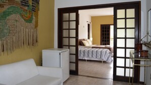 Una habitación con una cama, una mesita, una silla y un tapiz colgado en la pared.