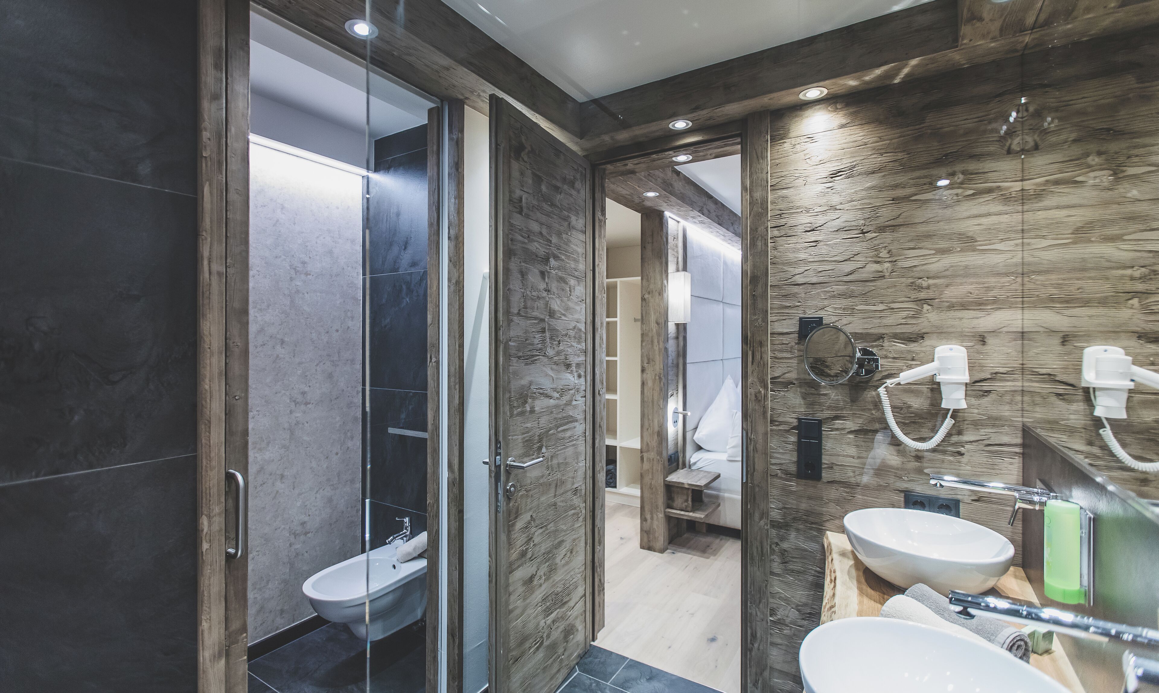 Un bagno moderno con doccia vetrata, lavandino bianco e mobile vanitario in legno.