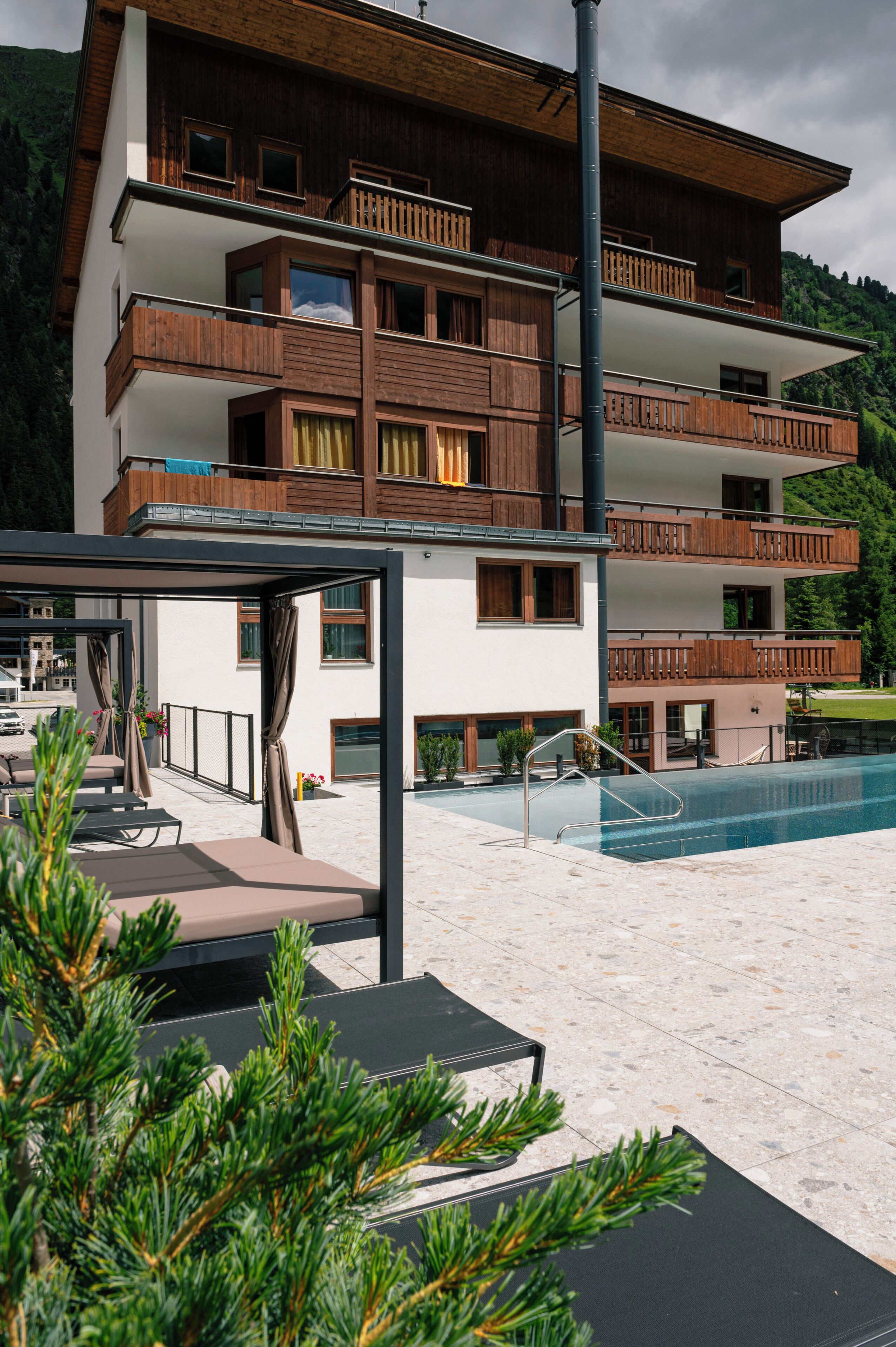 Un immeuble à plusieurs étages doté de balcons, d’une piscine et d’un espace extérieur aménagé pour s’asseoir.