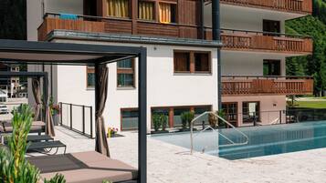 Un immeuble à plusieurs étages doté de balcons, d’une piscine et d’un espace extérieur aménagé pour s’asseoir.