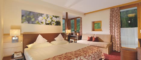 Una habitación de hotel con una cama grande, un escritorio, una silla y un ventanal con cortinas.