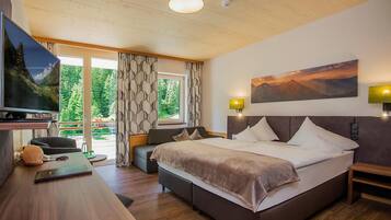 A modern hotel room with a large bed, a desk with a laptop, a television, and a scenic view through the window.
