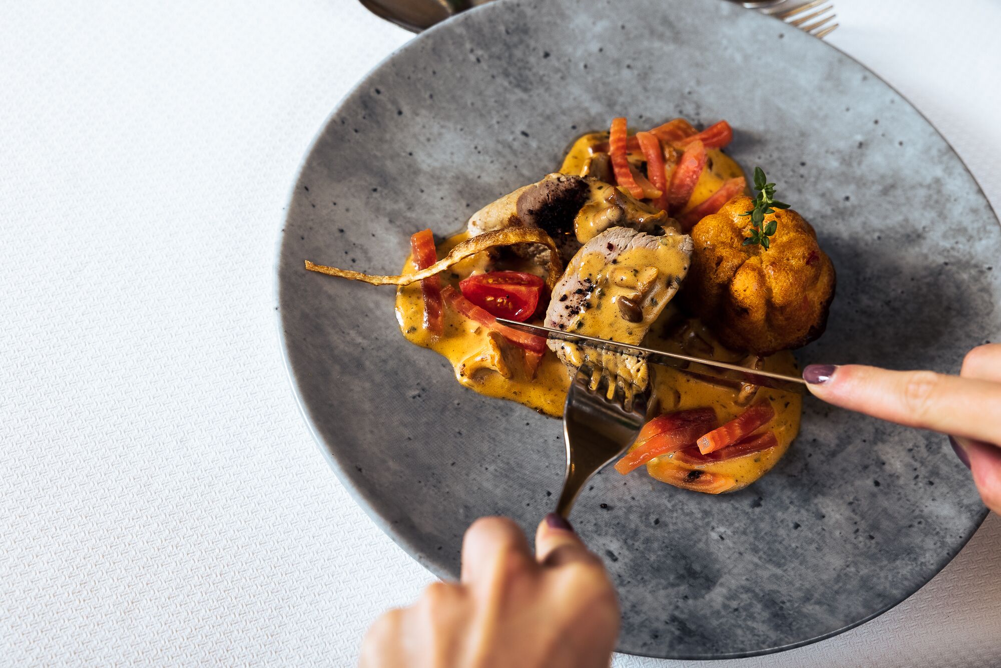 Un plato con brochetas de pollo a la parrilla, verduras y un muffin.