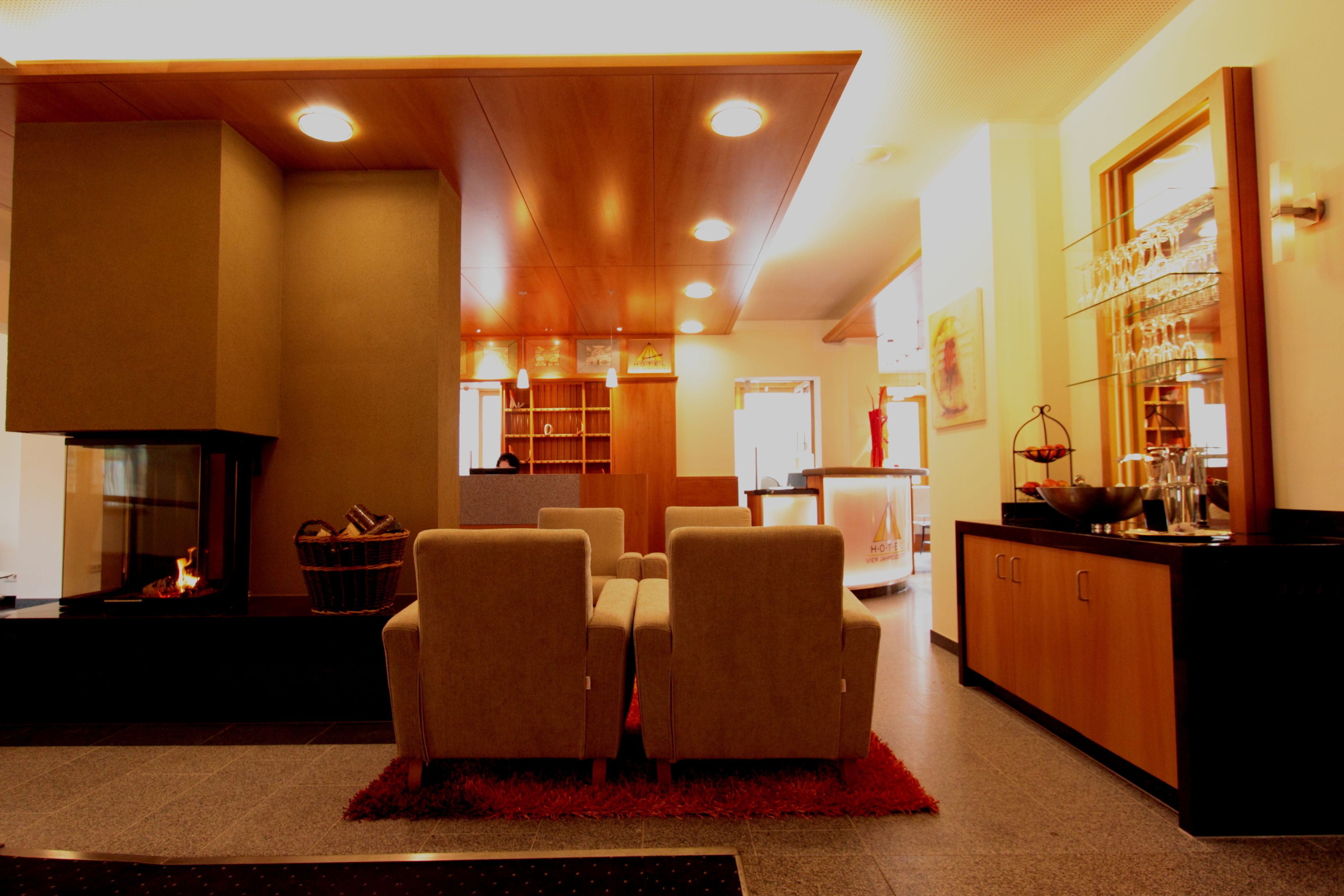 A hotel lobby with a fireplace, seating area, and a bar with glasses.
