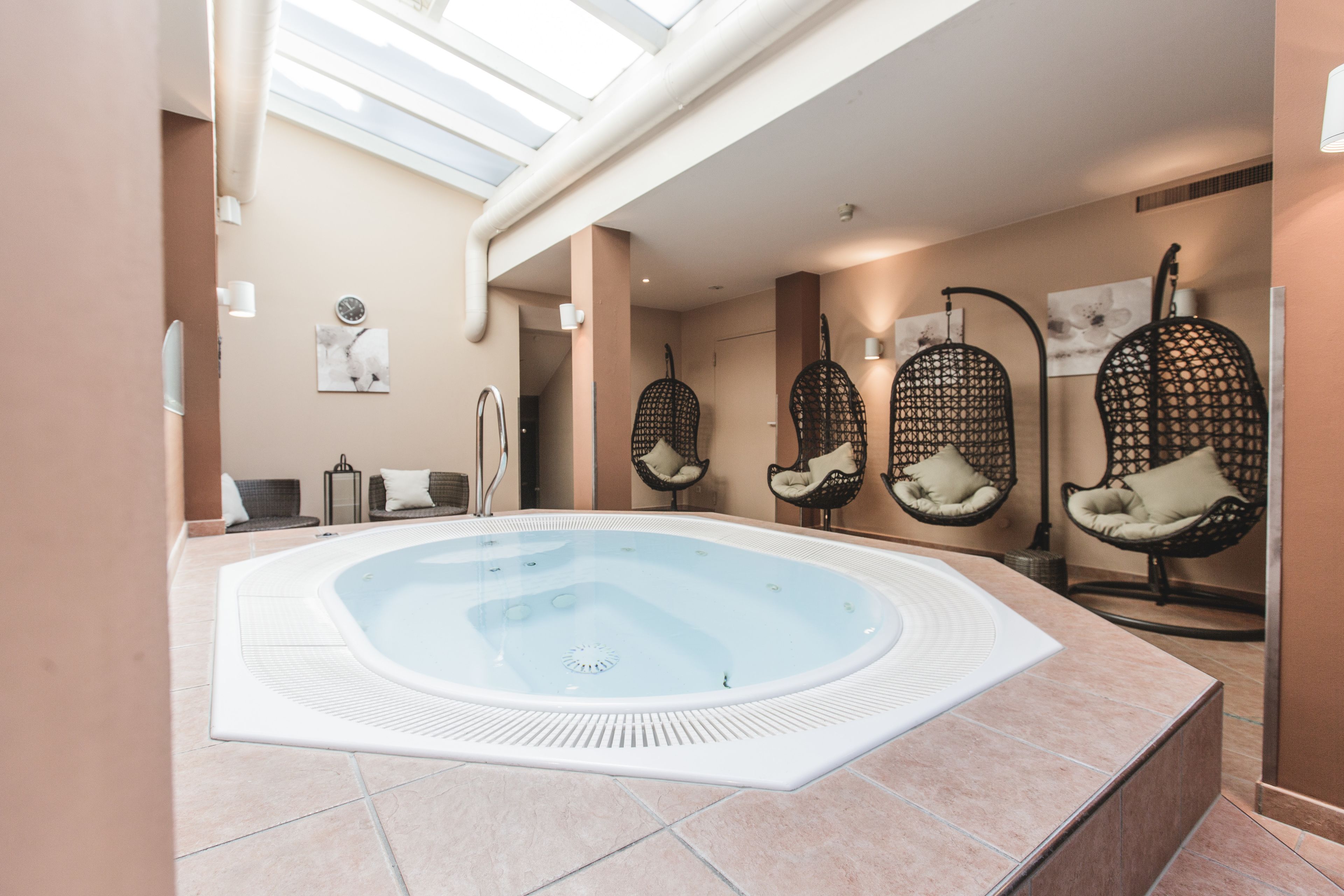 A spa area with a hot tub, wicker chairs, and a ceiling skylight.