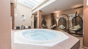 A spa area with a hot tub, wicker chairs, and a ceiling skylight.
