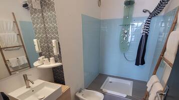 A modern bathroom with a sink, bidet, and bathtub.