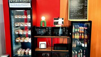 A food service area with a refrigerator displaying various food items, a menu board, and a microwave.