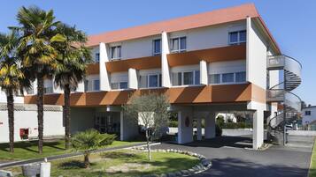 A modern hotel with a red roof, multiple balconies, and a spiral staircase.