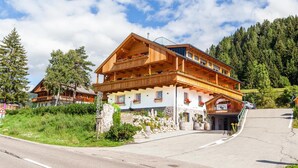 Un hôtel de style chalet en bois, doté de balcons, de fondations en pierre et offrant une vue sur les montagnes.