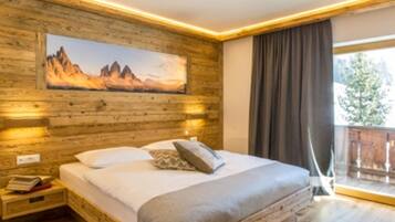 A bedroom with a wooden wall, a bed with pillows, a nightstand, and a painting of mountains.