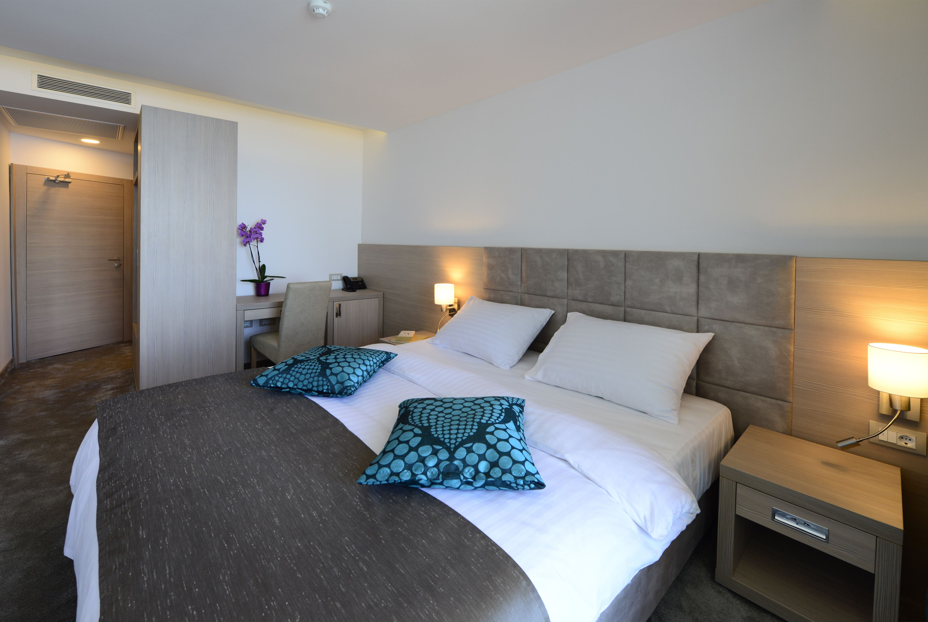 Une chambre d’hôtel avec un grand lit, deux tables de chevet, un bureau et une chaise.