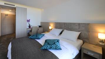 Une chambre d’hôtel avec un grand lit, deux tables de chevet, un bureau et une chaise.