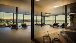 A spacious balcony with large windows offering a view of a coastal city and the sea. - Grand Hotel Adriatic II (Opatija)