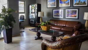 A modern living room with a leather sofa, a glass coffee table, and a large potted plant. - Hotel Mazatlan (Mazatlán)
