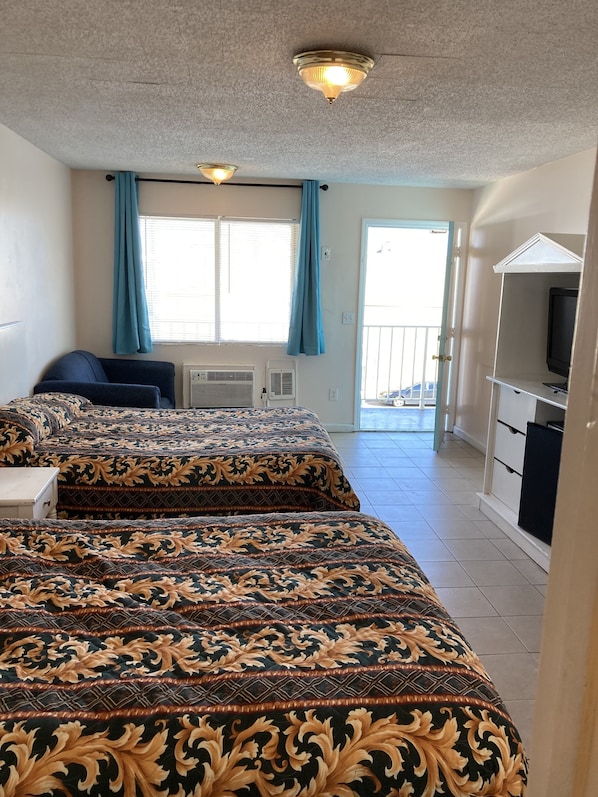Une chambre d’hôtel avec deux lits, une télévision, un balcon et un ventilateur de plafond.
