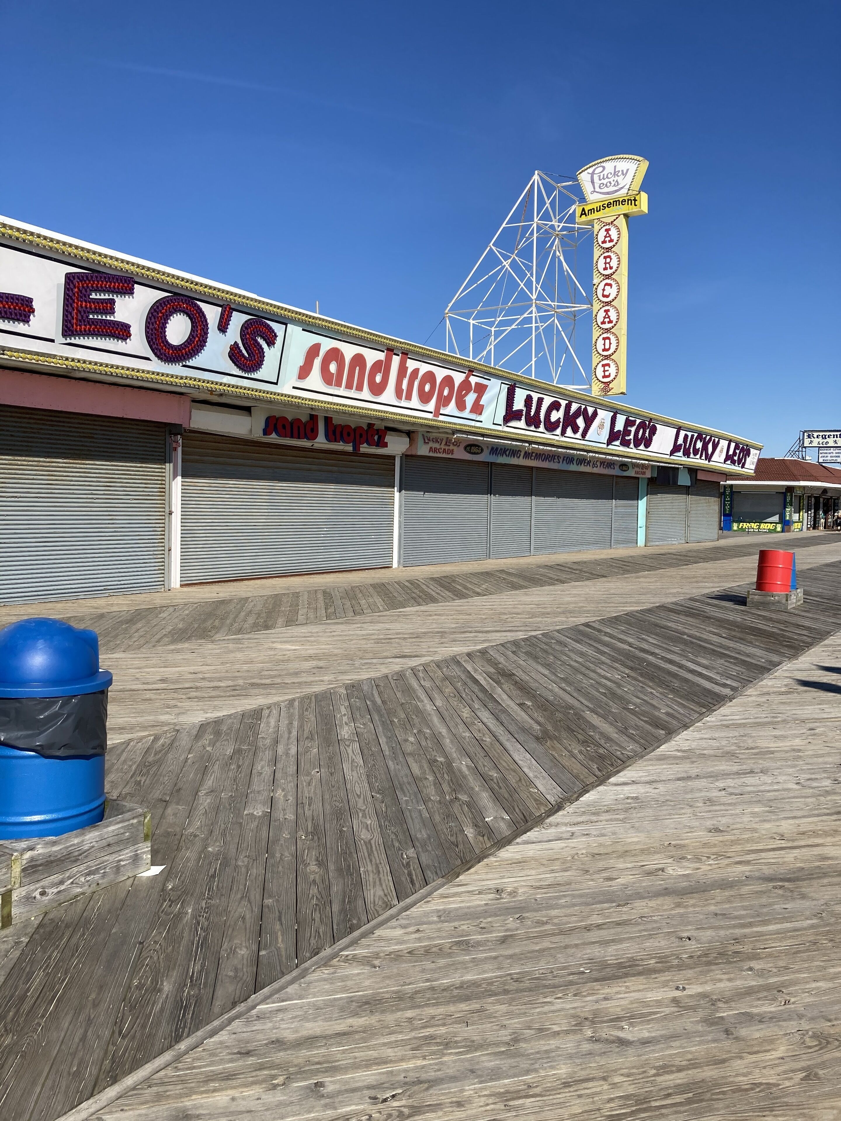 A boardwalk with closed shops, including 'Sandtropez' and 'Lucky Leo's'.