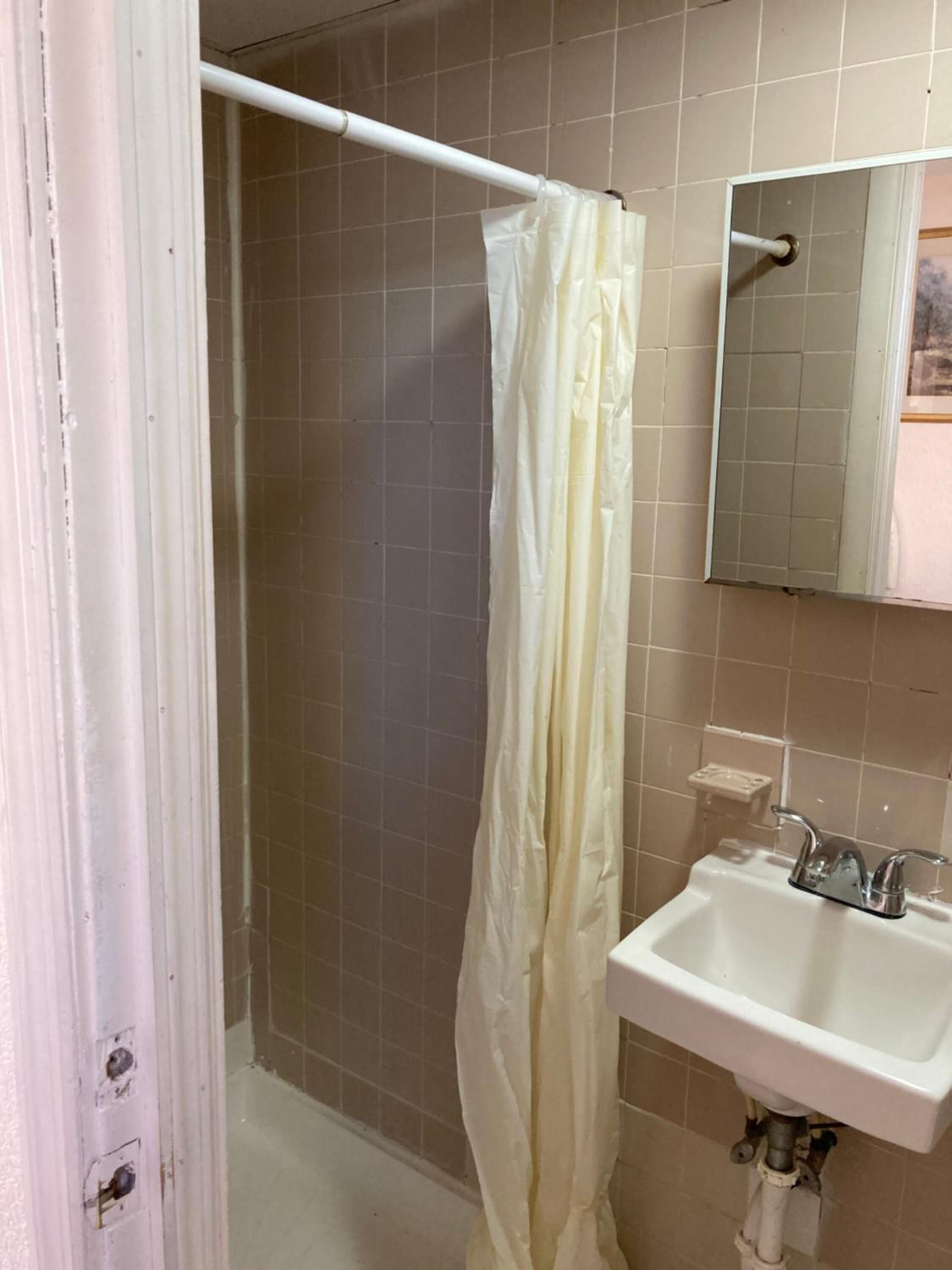 A bathroom with a shower, a sink, and a mirror.