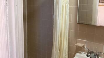 A bathroom with a shower, a sink, and a mirror.