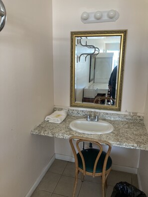 Une salle de bain avec un comptoir en marbre, un lavabo, un miroir avec un cadre doré et une chaise en bois.
