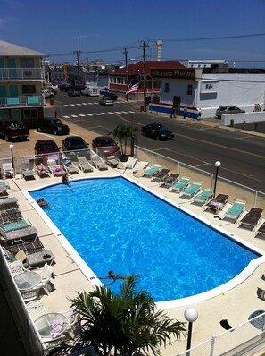 Une piscine avec des chaises longues et vue sur la rue.