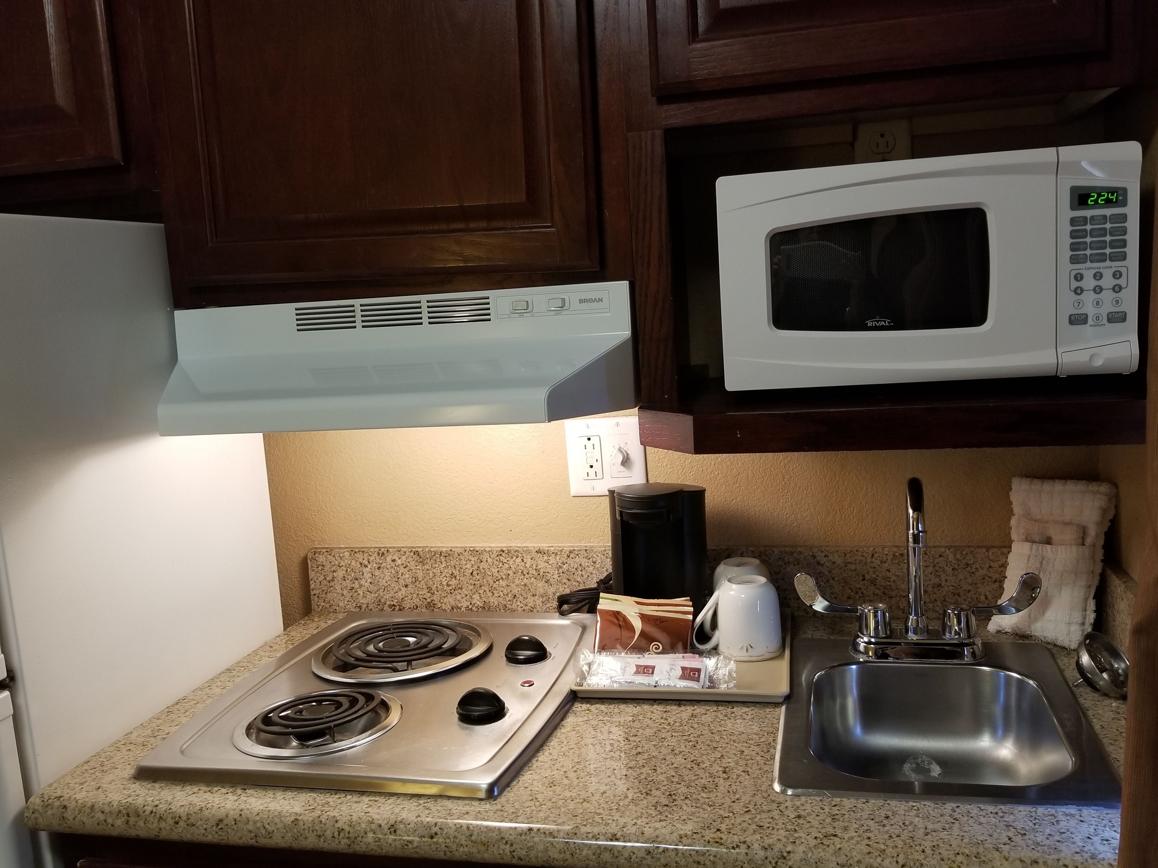 Une petite cuisine équipée d’une cuisinière, d’un four à micro-ondes et d’un évier.