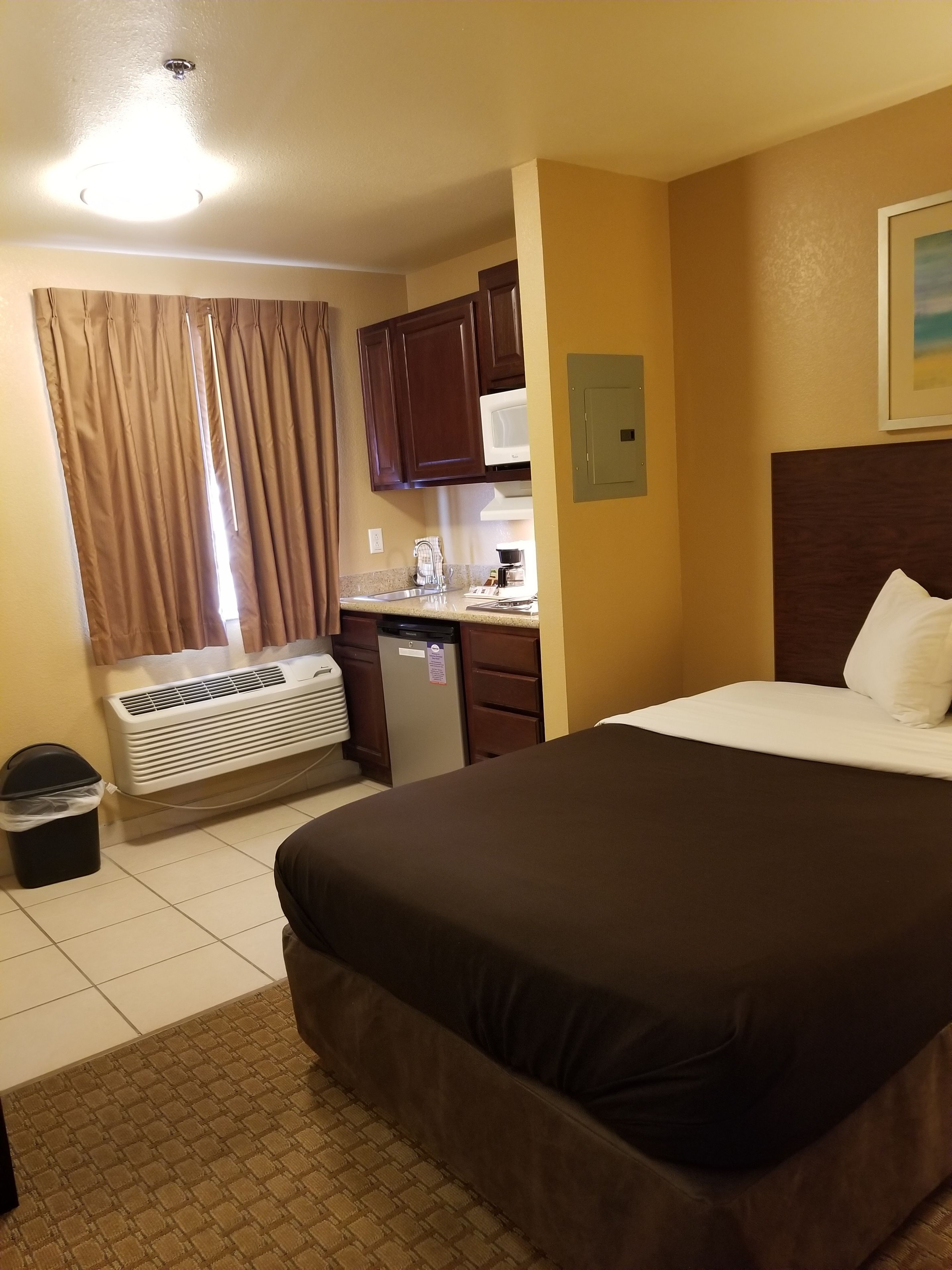 Une chambre d’hôtel avec un grand lit, une kitchenette, un four à micro-ondes, un radiateur et une poubelle.