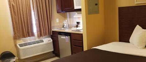 Une chambre d’hôtel avec un grand lit, une kitchenette, un four à micro-ondes, un radiateur et une poubelle.