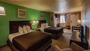 Habitación de hotel con dos camas, un escritorio, una silla y un televisor.